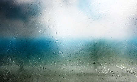Rain drops on window glass with blurred background. Rainy weather background.の写真素材