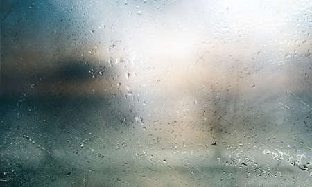 Water drops on glass with blurred background. Rainy weather concept.の写真素材