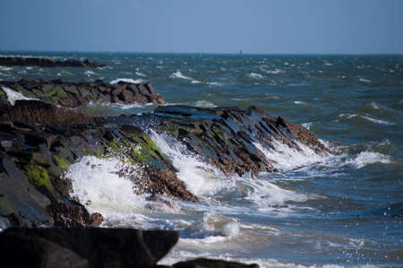 Waves crashing into a rocky shoreline near high tide, known to be a deadly current area 