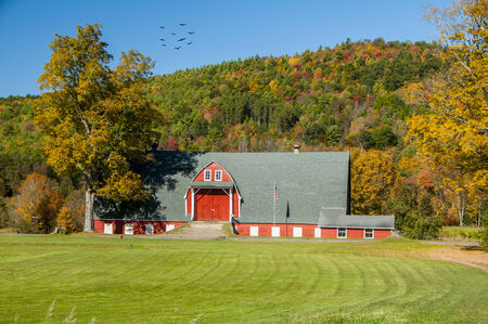 A large well maintained barn with a mountain of foliage in the backgroundのeditorial素材