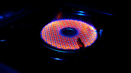 Round burner burns red orange blue flame in the darkの写真素材
