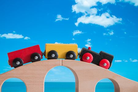 Colorful train toy on wooden bridge with bluesky backgroundの写真素材