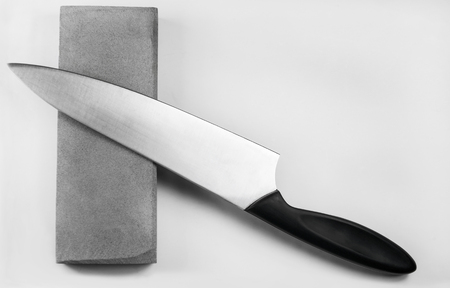 Sharpening a knife on a whetstone, isolated on white backgroundの写真素材