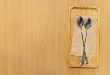 Wooden tray with spoons and tissue paper on wooden table, top view, copy spaceの写真素材