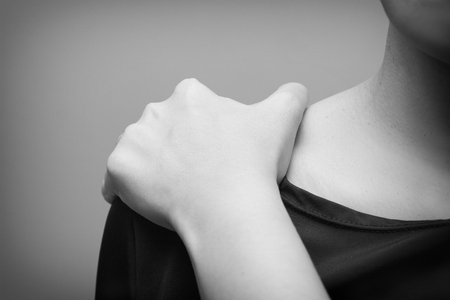 Young woman suffering from pain in shoulder,  Pain in the human body on a gray background- Black and whiteの写真素材