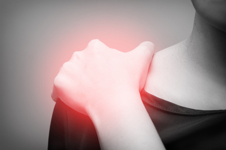Young woman suffering from pain in shoulder,  Pain in the human body on a gray background with red spot- Black and whiteの写真素材