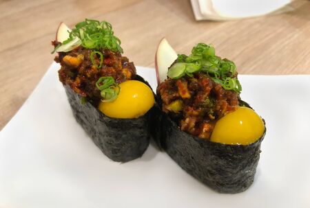 Gunkan maki yukke or sushi topping with spicy minced beef and raw quail egg yolkの写真素材