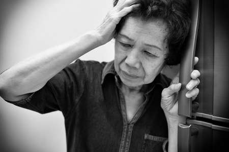 Elderly Asian woman holding her head, having a strong headache and fever. Black & white toneの写真素材
