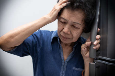 Elderly Asian woman holding her head, having a strong headache and fever.の写真素材