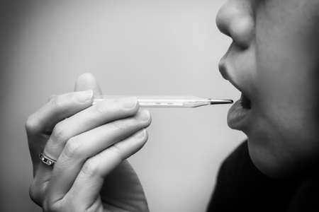 Asian young woman drinking a fresh white paper cup of water or other beverage. Black and white tone.の写真素材
