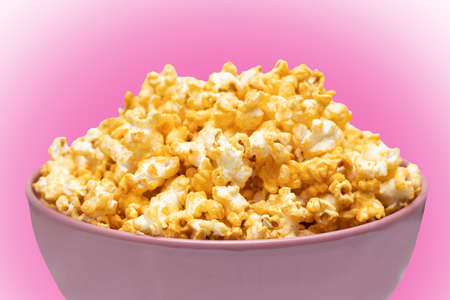 Popcorn in pink big bowl isolated on pink background. Unhealthy food concept. Health promotion concept.の写真素材