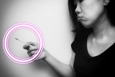 Asian woman looking at  clinical thermometer on her hand for checking temperature. With anxiety mood. Black and white tone with circle wave on thermometer. Diagnosis and test COVID-19.の写真素材