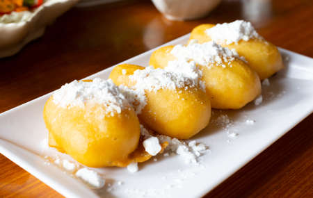 Vietnamese fried banana dough topping with Powdered sugar or icing sugar. serving on white square plateの写真素材