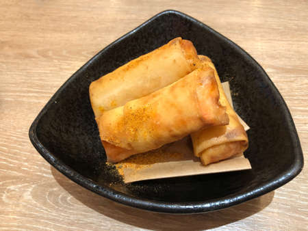 Deep Fried Spring Rolls serving on black plate, classic snack food made with ground pork, matchstick cut carrots, sliced cabbage and thinly sliced onion all wrapped up and fried until goldenの写真素材