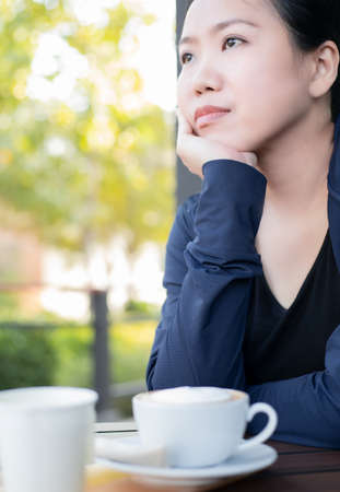 Asian girl enjoying life with a cup of hot coffee at the outside of cafe. Vacation conceptの写真素材