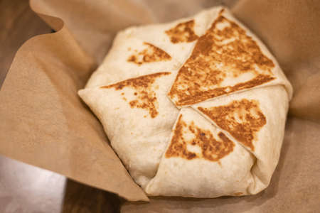 Mexican burritos wraps with round shape, serving on paper wrap.