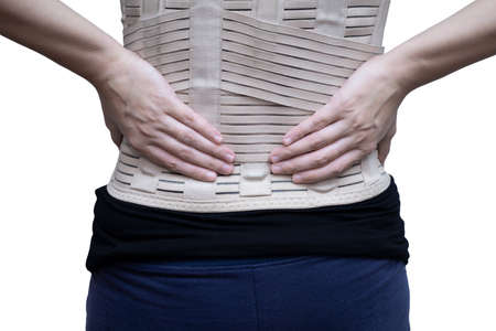 Woman in black t-shirt wearing back support belt for back pain and spinal support. Medical care concept. isolated on white backgroundの写真素材