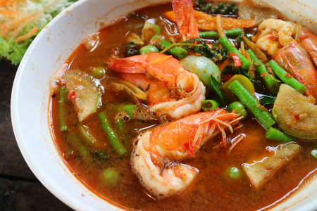 Spicy shrimp with red jungle curry serving on white bowl, traditional of Thai food. Healthy food concept. Variety of herbsの写真素材