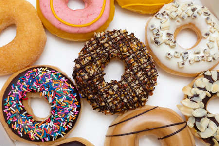 Top view of donuts set with chocolate glazed, sprinkled nuts and splatters of glaze. Isolated on white background.の写真素材