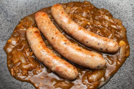 Wurst sausage in onion sauces serving on stone pan. Traditional German food.の写真素材