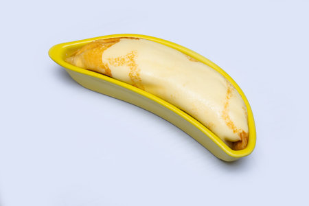 Cold crepes filled with banana are arranged in a yellow banana shaped ceramic plateの写真素材