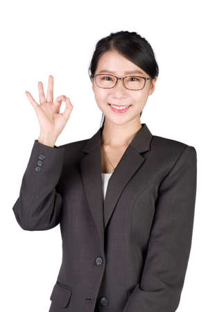 Young smiling businesswoman showing okay hand gesture, on white background. Asian model in business success concept.の写真素材