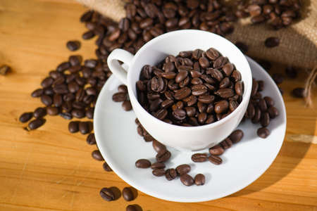 Roast coffee beens in a cup on wooden table.の写真素材
