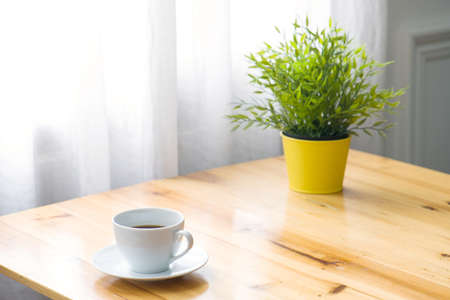 A cup of coffee and a pot of plants on a wooden table by the window. Relax concept. Casual concept.の写真素材