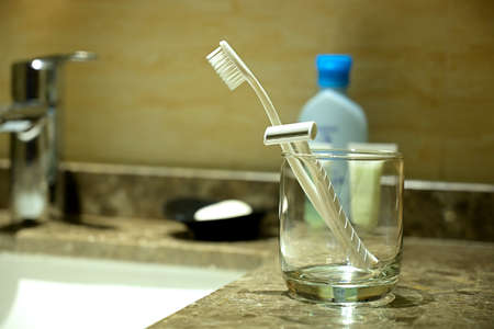 Glass with razor, toothbrush on the table in a bathroom.の写真素材