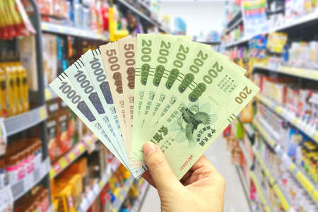 Taipei, Taiwan-Oct 11, 2021: Man's hand hold the Quintuple Stimulus Voucher in a grocery store.のeditorial素材