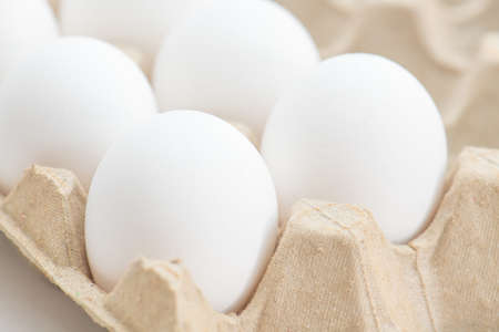 Fresh eggs in carton box on white backgroundの写真素材