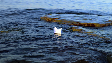 Paper boat ship floats in blue water in sea, sailboat symbol of shipping, travel concept, sailing