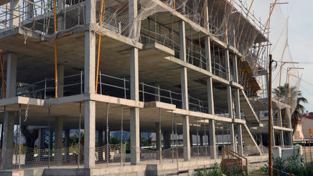 Multi-story concrete building is under construction, featuring scaffolding and safety nets. Project...