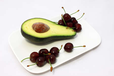 avocado and fresh cherry on the white plateの写真素材
