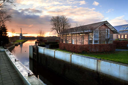 view on Dutch village before the sunset, with small channel, windmill and farmsのeditorial素材