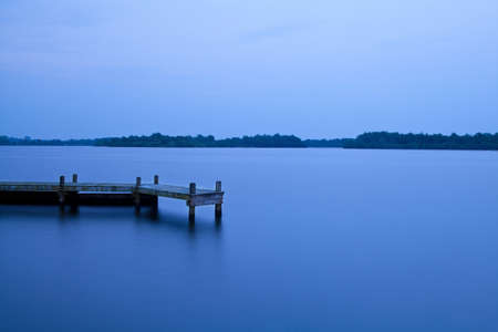 wooden pier on the lake at dusk after sunsetの写真素材