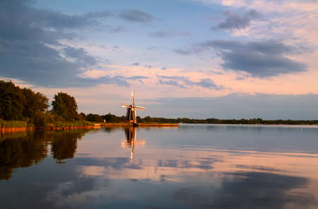 windmill on lake at sunset in Groningenの写真素材