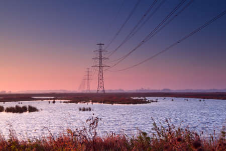 high-voltage electricity line over lakes at early colorful sunriseの写真素材