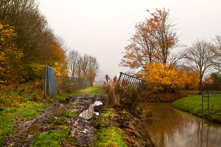 dirty ground road with few puddles in fog