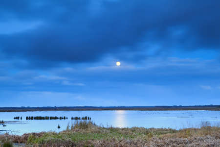 full moon at night over lake with long exposureの写真素材