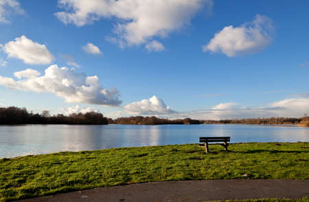 lonely bench with view on lake and beautiful skyの写真素材