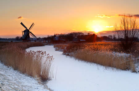 dramatic sunrise by Dutch windmill during winterの写真素材