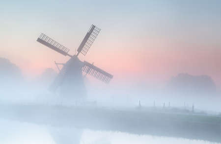 Dutch windmill in dense fog at summer sunriseの写真素材
