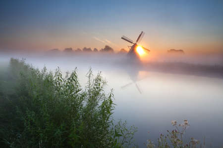 summer sunrise over river and windmill, Groningen, Netherlandsの写真素材