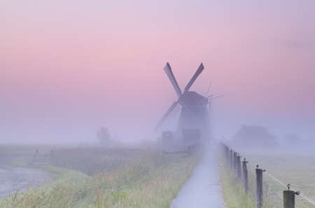 charming Dutch windmill in morning mist at sunriseの写真素材