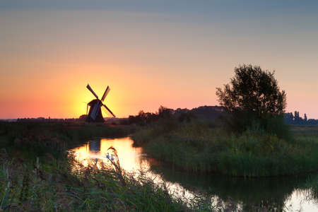 shining windmill during sunrise over river, Hollandの写真素材