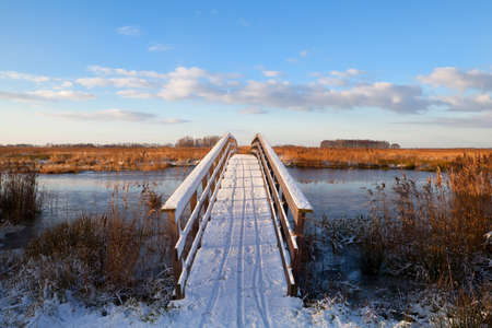wooden bridge through river in snow during winter, Groningen, Netherlandsの写真素材