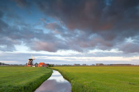 Dutch windmill by river at sunrise, Hollandの写真素材