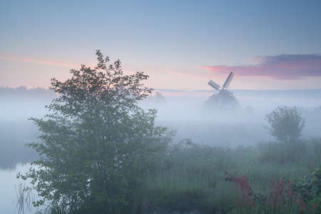 windmill and river at misty sunrise, Hollandの写真素材