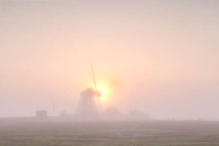 windmill silhouette in dense fog at sunrise, Hollandの写真素材